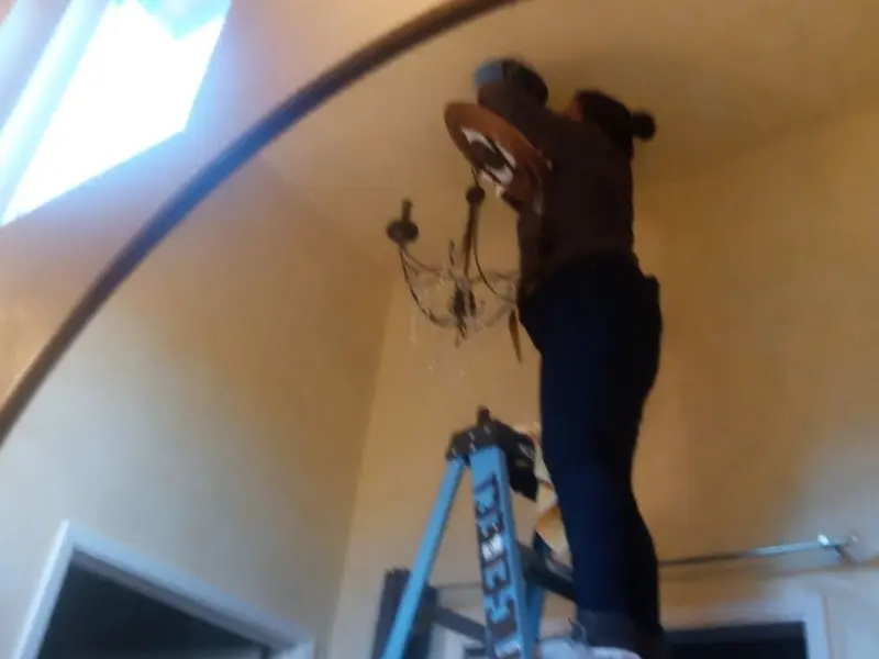 Electrician installing a chandelier in a Fairland residence
